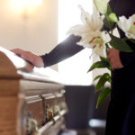 woman with lily flowers and coffin at funeral